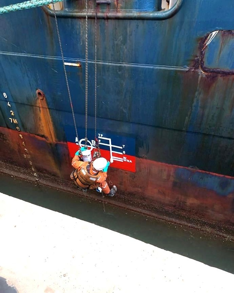 Dupla de técnicos em acesso por cordas inspecionando linha d'água do casco