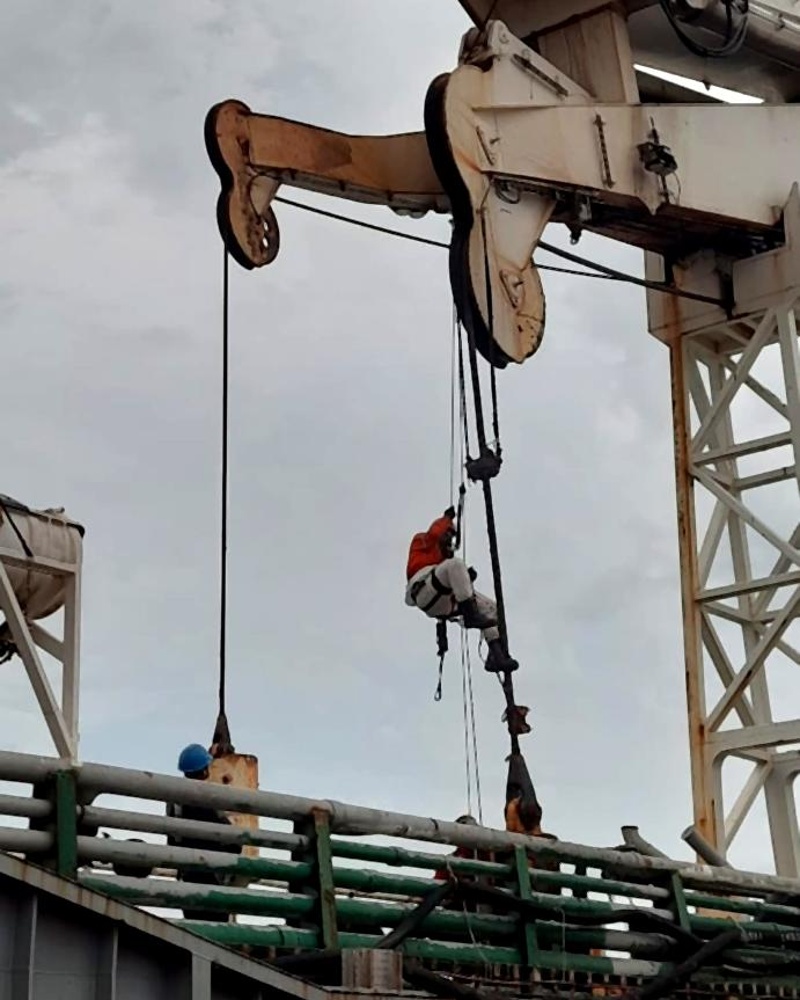 Técnico em rapel sob lança de guindaste em operação portuária