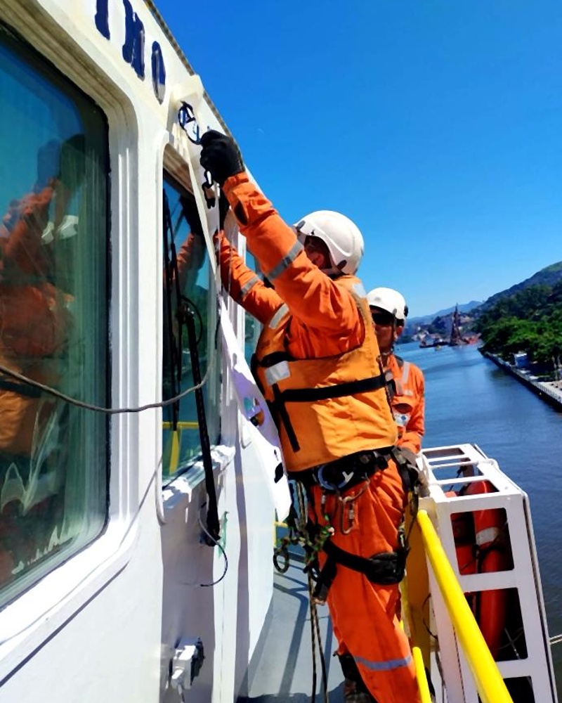 Técnicos em manutenção de janela de cabine de embarcação portuária